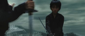 Movie still from “Goemon” (2009), directed by Kazuaki Kiriya – A young boy holding a sword in front of a person; Medium shot, Low angle