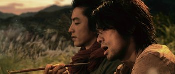 Movie still from “Goemon” (2009), directed by Kazuaki Kiriya – Two young men are eating food while standing outside; Close Up shot, Low angle