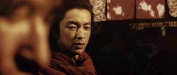 Movie still from “Goemon” (2009), directed by Kazuaki Kiriya – A man in a red shirt is looking at the camera; Close Up shot, Low angle