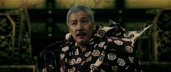 Movie still from “Goemon” (2009), directed by Kazuaki Kiriya – An older man with a gray beard wearing a black and gold jacket; Close Up shot, Low angle