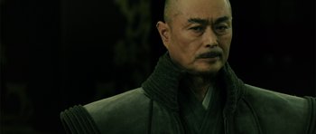 Movie still from “Goemon” (2009), directed by Kazuaki Kiriya – An older man with a shaved head wearing a black robe; Close Up shot, Low angle
