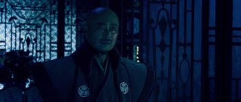 Movie still from “Goemon” (2009), directed by Kazuaki Kiriya – A man with a bald head wearing a robe; Medium shot, Over the shoulder angle