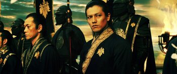 Movie still from “Goemon” (2009), directed by Kazuaki Kiriya – A man in a black and gold outfit with a sword in front of a painting; Close Up shot, Low angle