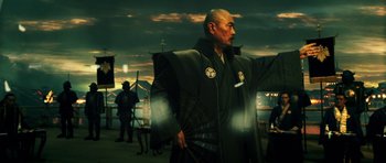 A man in a black outfit holding a black umbrella
