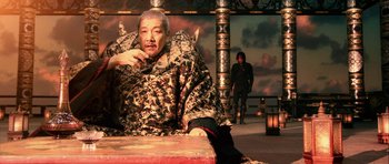 Movie still from “Goemon” (2009), directed by Kazuaki Kiriya – An older man sitting on top of a red bench; Medium shot, High angle