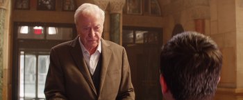 Movie still from “Going in Style” (2017), directed by Zach Braff – An older man wearing a suit looking at himself in the mirror; Medium shot, Over the shoulder angle