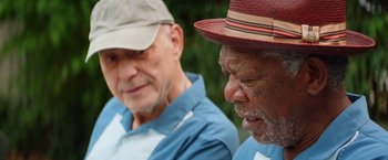 Movie still from “Going in Style” (2017), directed by Zach Braff – Two older men sitting next to each other in a park; Close Up shot, Over the shoulder angle