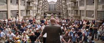 Movie still from “Going in Style” (2017), directed by Zach Braff – A group of people sitting in a building with a man standing in front of them; Wide shot, High angle