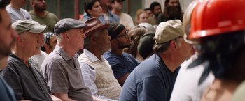 Movie still from “Going in Style” (2017), directed by Zach Braff – A group of people sitting in a room watching something; Medium shot, Over the shoulder angle