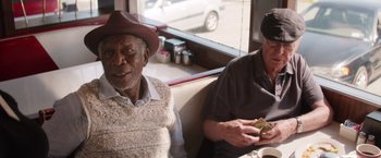 Movie still from “Going in Style” (2017), directed by Zach Braff – Two older men sitting on a bench next to each other; Medium shot, Over the shoulder angle