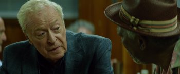 Movie still from “Going in Style” (2017), directed by Zach Braff – An older man wearing a suit and a hat; Close Up shot, Over the shoulder angle