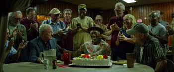 Movie still from “Going in Style” (2017), directed by Zach Braff – An older man sitting in front of a birthday cake; Medium shot, High angle