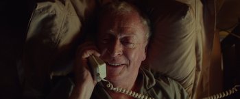 Movie still from “Going in Style” (2017), directed by Zach Braff – An older man talking on a phone while laying in bed; Close Up shot, Overhead angle