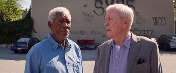 Movie still from “Going in Style” (2017), directed by Zach Braff – Two older men standing next to each other on the street; Medium shot, Over the shoulder angle