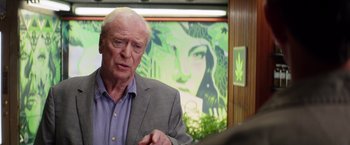 Movie still from “Going in Style” (2017), directed by Zach Braff – An older man in front of a painting of a woman; Medium shot, Over the shoulder angle