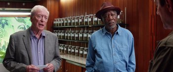 Movie still from “Going in Style” (2017), directed by Zach Braff – A man in a red hat standing next to a man in a blue shirt; Medium shot, Low angle