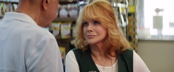 Movie still from “Going in Style” (2017), directed by Zach Braff – An older woman with blonde curly hair and a cross on her chest; Close Up shot, Over the shoulder angle