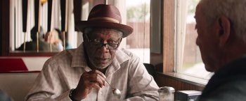 Movie still from “Going in Style” (2017), directed by Zach Braff – An older man wearing a hat and holding a spoon in his hand; Close Up shot, Over the shoulder angle