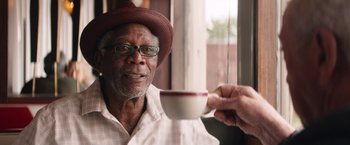 Movie still from “Going in Style” (2017), directed by Zach Braff – An older man holding a coffee cup in front of a window; Close Up shot, Over the shoulder angle