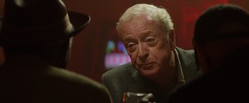 Movie still from “Going in Style” (2017), directed by Zach Braff – An older man sitting at a table with a glass of wine; Close Up shot, Over the shoulder angle