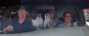 Movie still from “Going in Style” (2017), directed by Zach Braff – A group of men sitting in the back of a vehicle; Wide shot, High angle