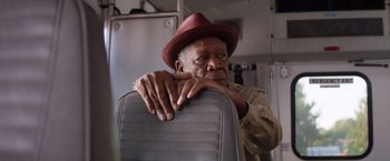 Movie still from “Going in Style” (2017), directed by Zach Braff – An older man wearing a red hat leaning on a chair; Close Up shot, Low angle