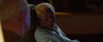 Movie still from “Going in Style” (2017), directed by Zach Braff – An older man sitting in a chair looking at the camera; Close Up shot, Over the shoulder angle
