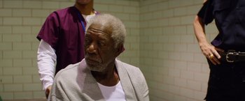 Movie still from “Going in Style” (2017), directed by Zach Braff – An older man sitting in front of a brick wall; Close Up shot, Over the shoulder angle