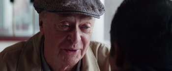 Movie still from “Going in Style” (2017), directed by Zach Braff – An older man wearing a hat looking at a younger man; Close Up shot, Over the shoulder angle