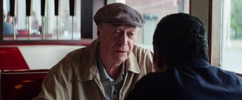 Movie still from “Going in Style” (2017), directed by Zach Braff – An older man wearing a hat talking to a younger man; Close Up shot, Over the shoulder angle
