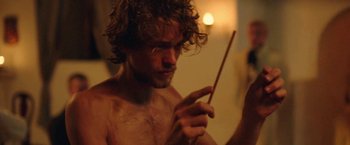 Movie still from “Gold Coast” (2015), directed by Daniel Dencik – A man holding a wooden stick in his hand; Close Up shot, Over the shoulder angle