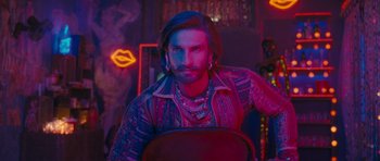 Movie still from “Goliyon Ki Raasleela Ram Leela” (2013), directed by Sanjay Leela Bhansali – A man with long dark hair sitting in front of a neon sign; Close Up shot, Low angle