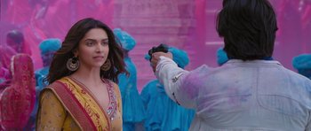 Movie still from “Goliyon Ki Raasleela Ram Leela” (2013), directed by Sanjay Leela Bhansali – A woman in a yellow and red dress is being photographed by a man in a blue suit; Medium shot, Over the shoulder angle