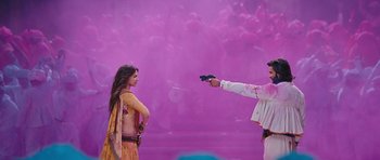 Movie still from “Goliyon Ki Raasleela Ram Leela” (2013), directed by Sanjay Leela Bhansali – A woman and a man are holding a gun in front of a purple background; Wide shot, Over the shoulder angle