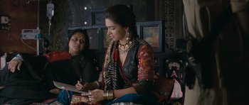 Movie still from “Goliyon Ki Raasleela Ram Leela” (2013), directed by Sanjay Leela Bhansali – A woman sitting next to another woman while writing on a piece of paper; Medium shot, Over the shoulder angle