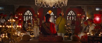 Movie still from “Goliyon Ki Raasleela Ram Leela” (2013), directed by Sanjay Leela Bhansali – A woman in a red and yellow dress sitting in a room; Wide shot, Low angle