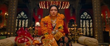 Movie still from “Goliyon Ki Raasleela Ram Leela” (2013), directed by Sanjay Leela Bhansali – A woman sitting in front of a stage with a lot of flowers around her neck; Medium shot, Low angle