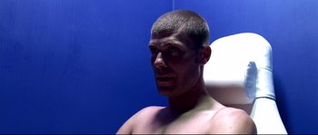 Movie still from “Gomorrah” (2008), directed by Matteo Garrone – A man with a shaved head looks into a mirror; Close Up shot, Low angle