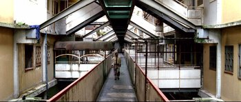 Movie still from “Gomorrah” (2008), directed by Matteo Garrone – A man is walking down a long walkway; Wide shot, High angle