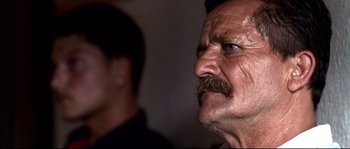 Movie still from “Gomorrah” (2008), directed by Matteo Garrone – An older man with a mustache looking up at the sky; Close Up shot, Over the shoulder angle