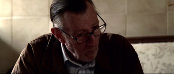 Movie still from “Gomorrah” (2008), directed by Matteo Garrone – An older man wearing glasses looking down at his face; Close Up shot, Over the shoulder angle