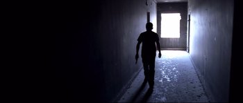 Movie still from “Gomorrah” (2008), directed by Matteo Garrone – A man walking down a hallway in a dark room; Wide shot, Low angle