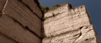 Movie still from “Gomorrah” (2008), directed by Matteo Garrone – A wall that has a bunch of plants growing on it; Extreme Wide shot, Low angle