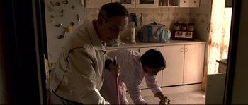 Movie still from “Gomorrah” (2008), directed by Matteo Garrone – A man and a woman cleaning the kitchen floor; Medium shot, High angle