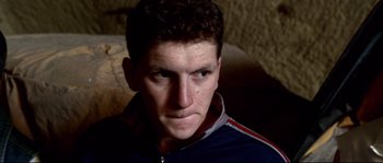 Movie still from “Gomorrah” (2008), directed by Matteo Garrone – A person wearing a blue and red jacket; Close Up shot, High angle