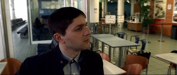 Movie still from “Gomorrah” (2008), directed by Matteo Garrone – A man sitting at a table in front of some tables; Close Up shot, Over the shoulder angle
