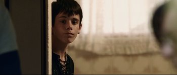 Movie still from “Gomorrah” (2008), directed by Matteo Garrone – A young man with a piercing is posing for a picture; Close Up shot, Low angle