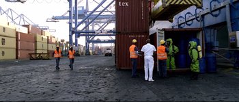Movie still from “Gomorrah” (2008), directed by Matteo Garrone – A group of people standing around a large container ship; Extreme Wide shot, High angle