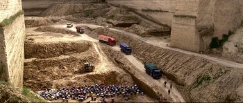 Movie still from “Gomorrah” (2008), directed by Matteo Garrone – A group of people standing on top of a dirt road; Extreme Wide shot, High angle
