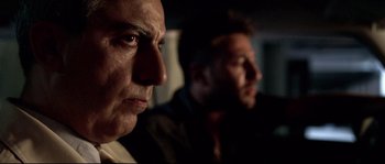 Movie still from “Gomorrah” (2008), directed by Matteo Garrone – Two men sitting next to each other in a dark room; Close Up shot, Low angle